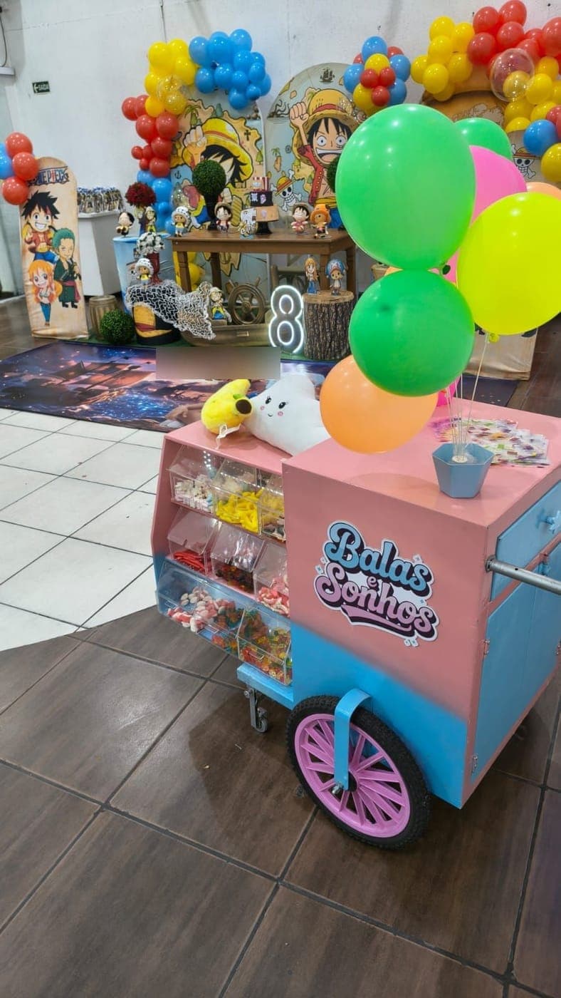 Carrinho Balas e Sonhos com balões em frente à decoração de uma festa com tema de One Piece