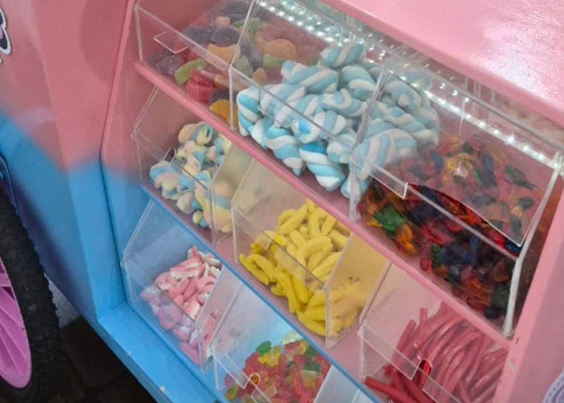 Potes de acrílico com doces variados: marshmallows torcidos, bananinhas, balas de goma e tubos azedinhos